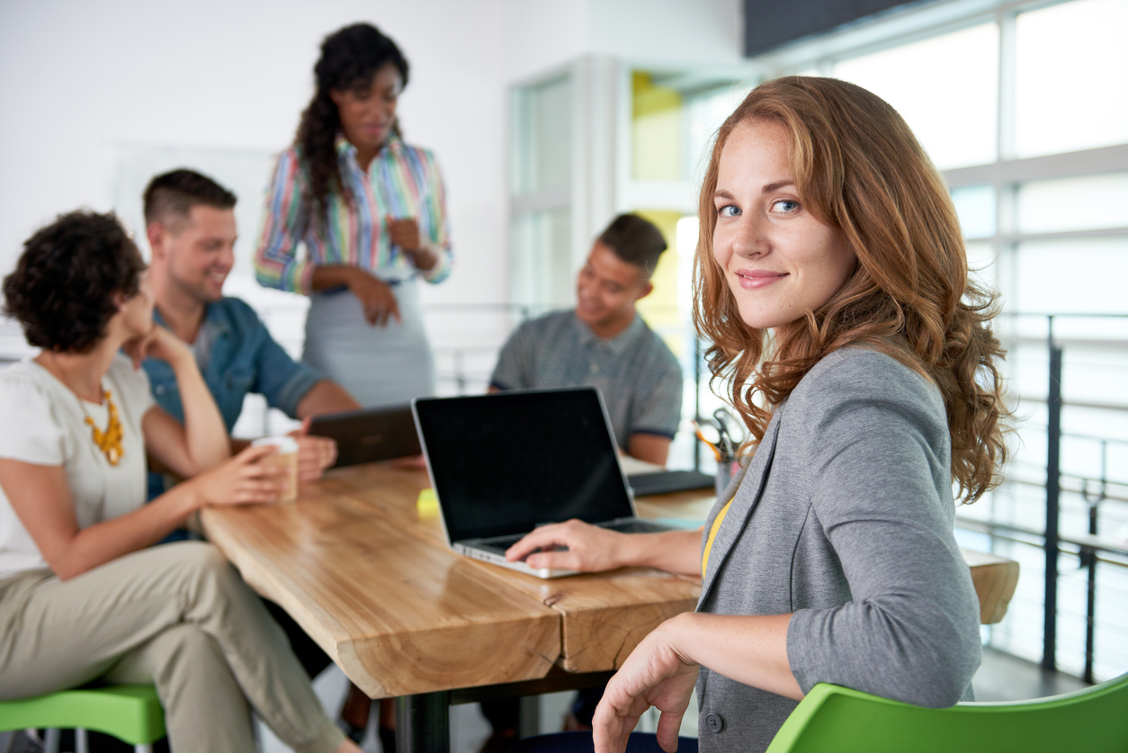 Creative blond businesswoman leading hes team in a friendly conversation about their next agency project. Build your personal brand.